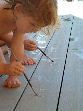 Enfants peignant avec de l'eau au bord de la piscine